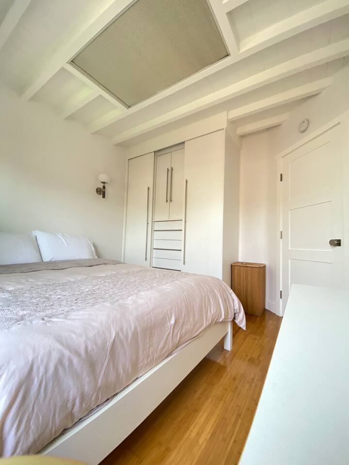 Quiet bedroom with soft bedding and hardwood floors.