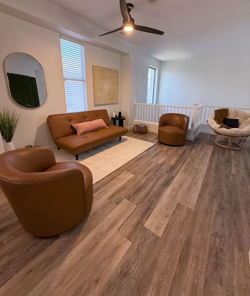 Open sitting area with accent chairs, sofa seating, natural light, and easy flow to the dining and living spaces.