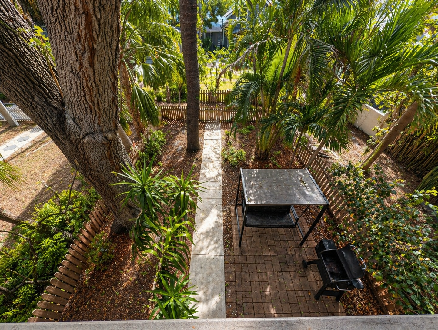 backyard with smoker, grill, swinging chair and fenced yard with Christmas lights at night 