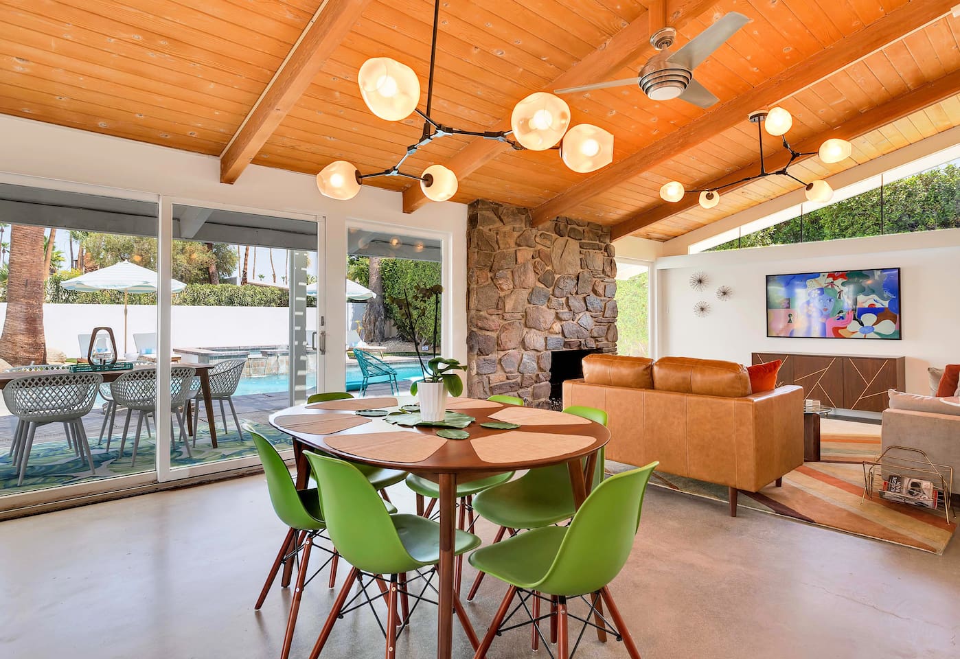 Great room with polished concrete floors, original hand-laid stone fireplace, dramatic lighting and Samsung Frame TV.