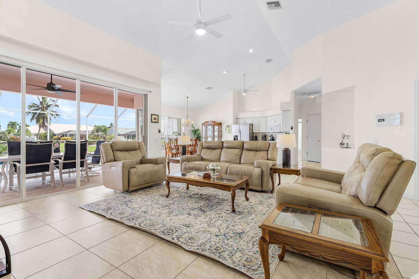 Spacious living room with cozy seating and a TV, offering seamless access to the pool, spa, and lanai for ultimate relaxation and fun!