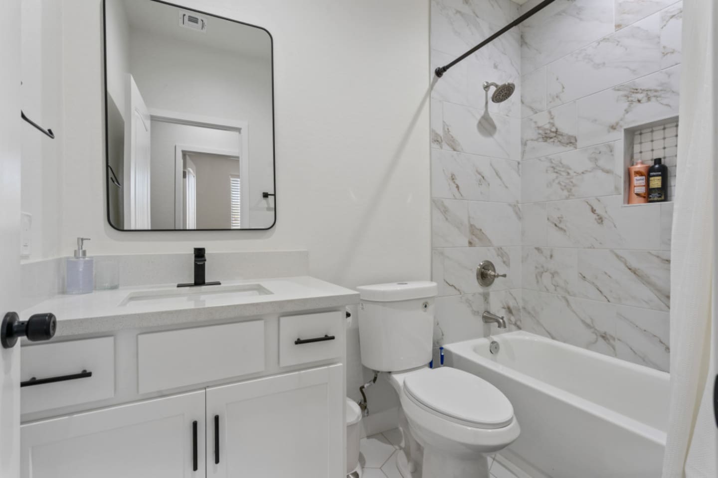 Guest bathroom with tub/shower combination, marble-style tile, vanity storage, and a clean modern layout.