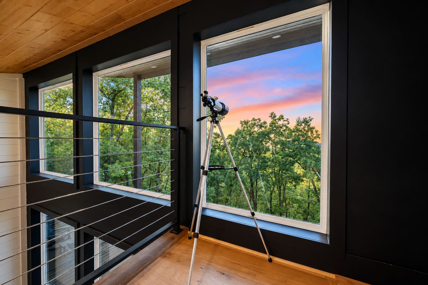 Loft lounge with telescope; ladder access beside the upper-level fireplace.