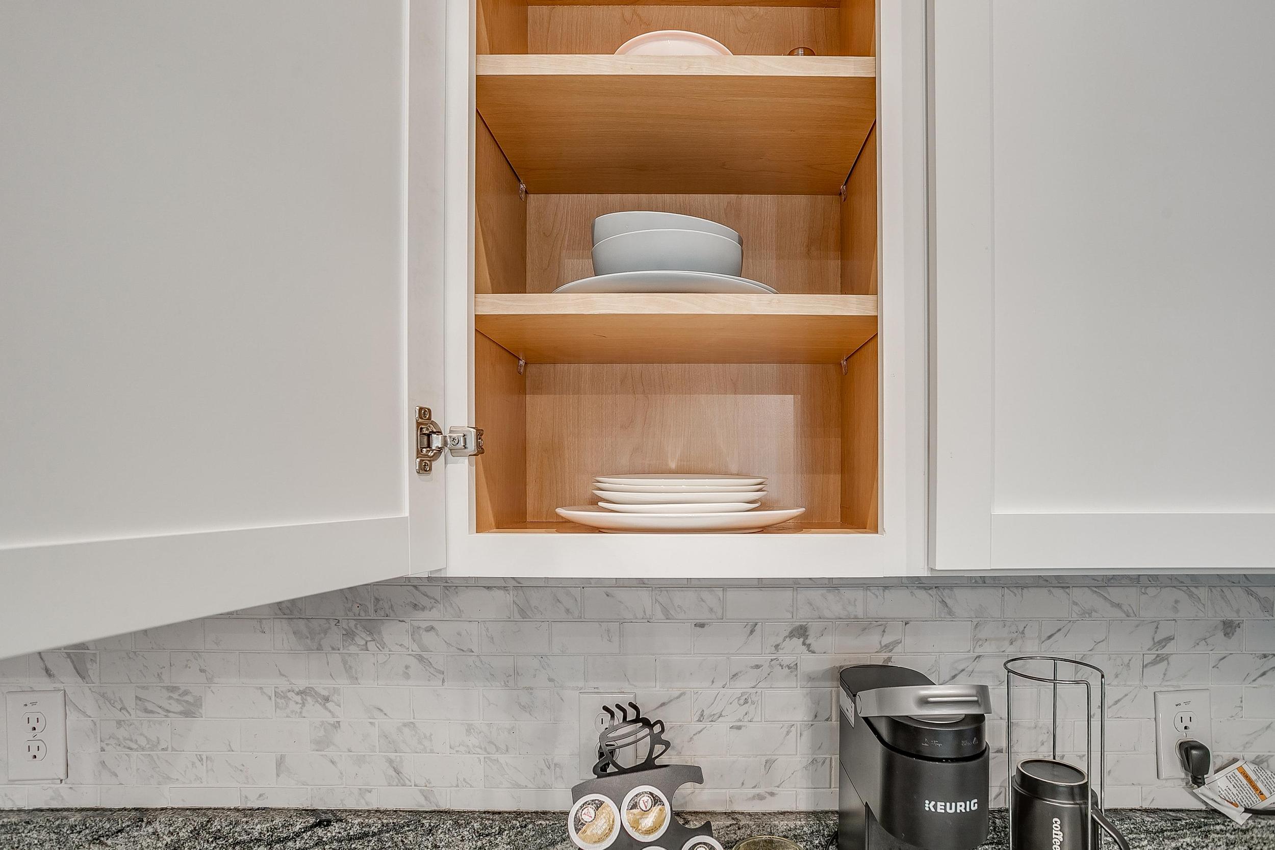 Cabinet stocked with dishes, plates, and glasses.