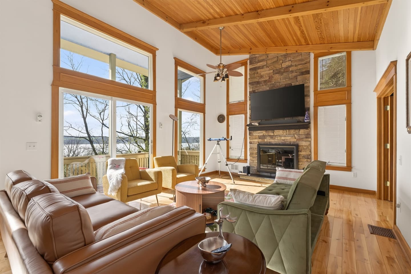 Spacious living room with fireplace, Smart TV, and stunning lake views through floor-to-ceiling windows—cozy up by the fire, enjoy movie nights, or use the telescope to take in nature and peaceful surroundings