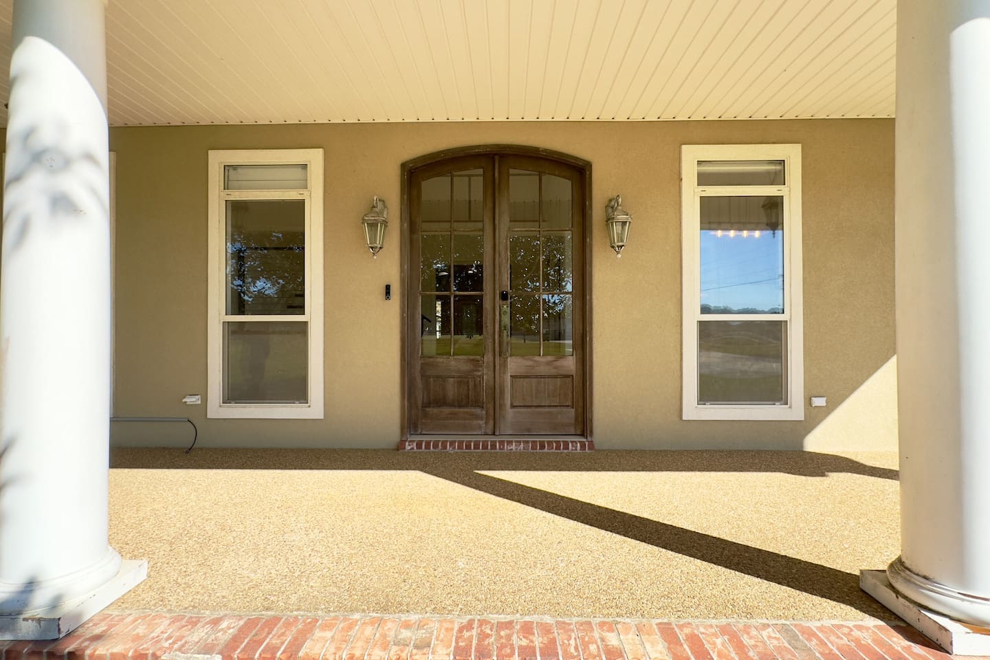 A grand double wooden door with arched glass panels creates a striking focal point at the entryway.