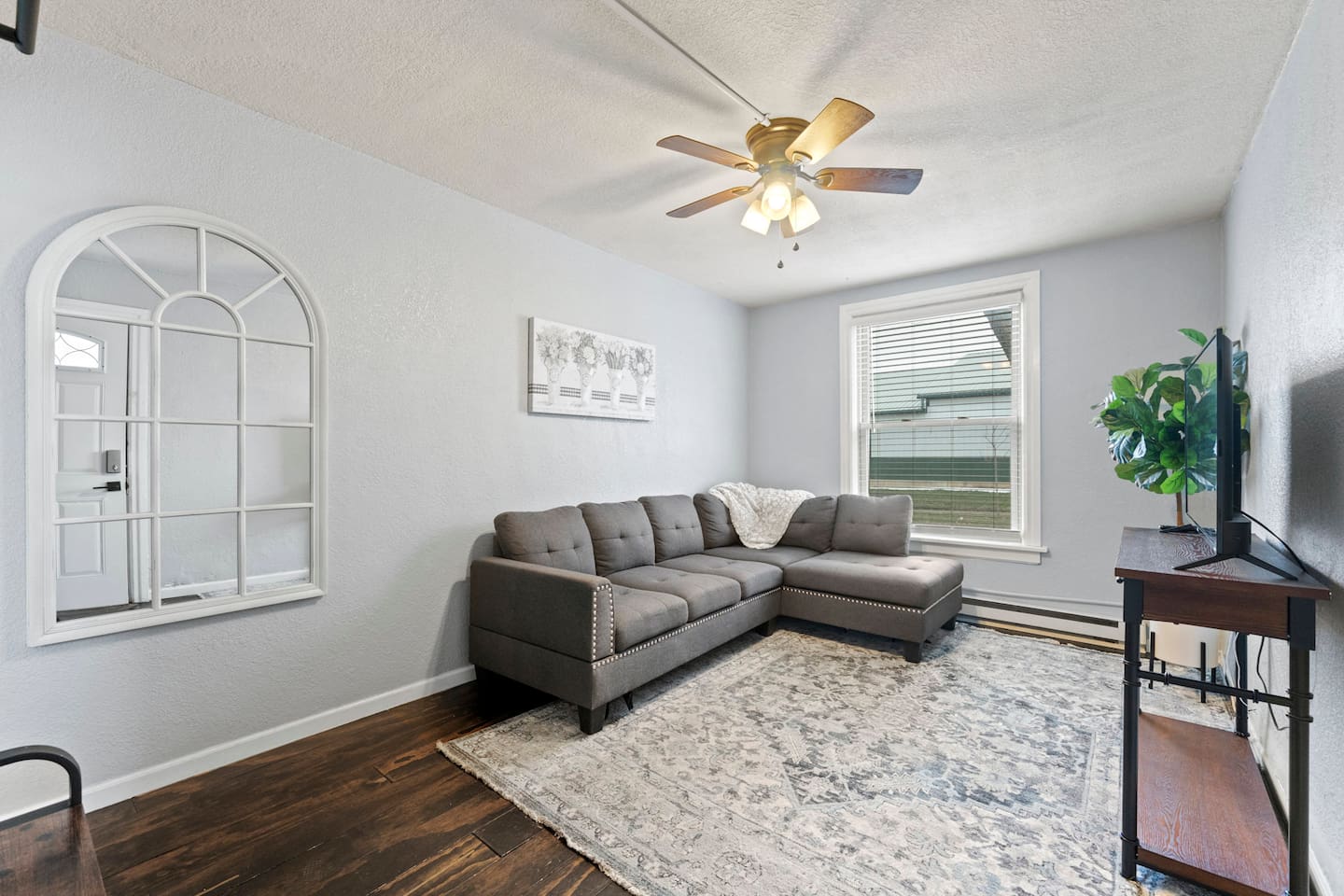 Relax in the living room, complete with a grey sectional couch and a TV for your entertainment and comfort.
