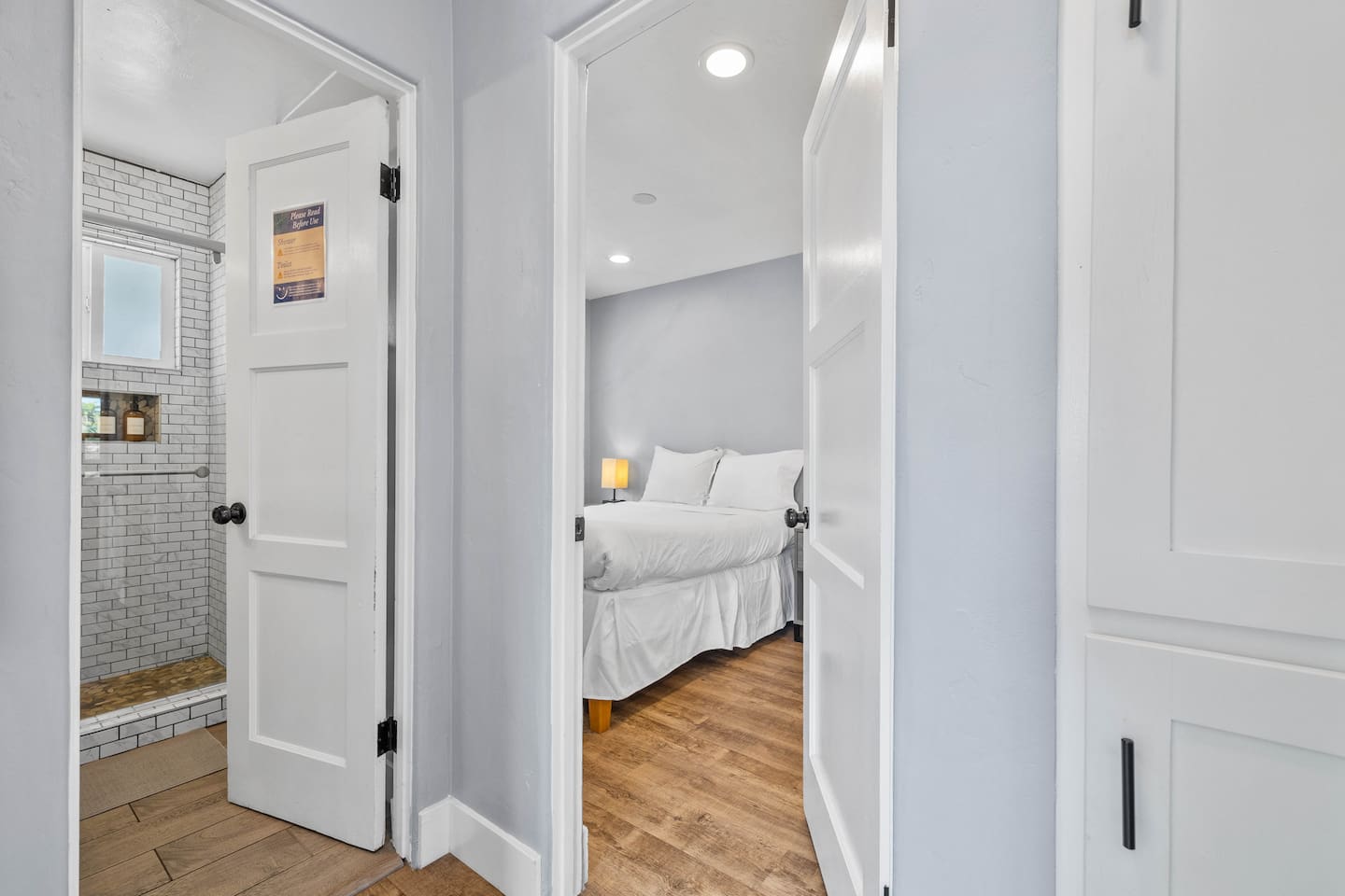 Relax in this inviting bedroom with a cozy bed, two chic lampshades providing warm lighting, and a large window showcasing stunning views. The elegant flooring and thoughtful design create the perfect space for a peaceful and comfortable retreat.