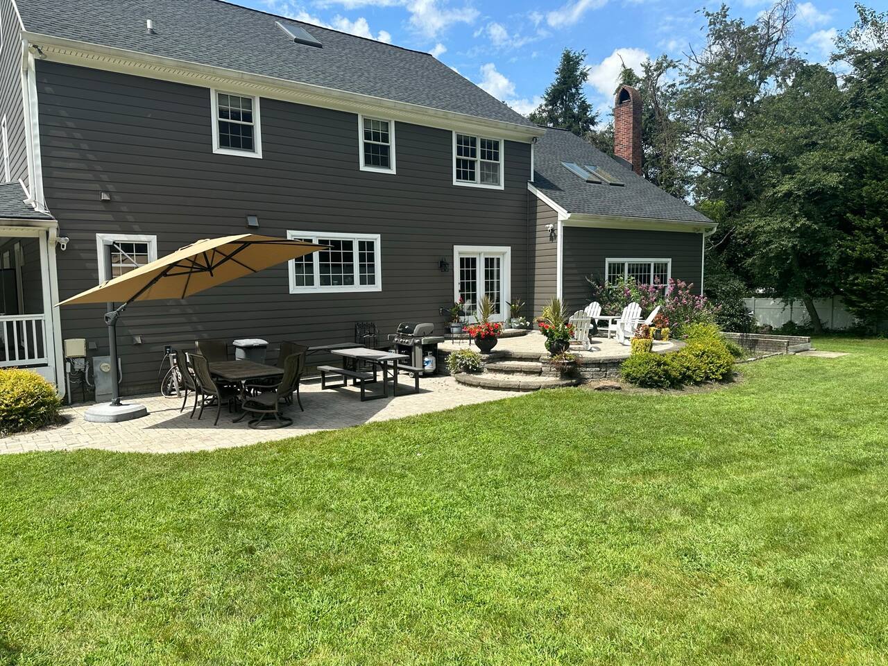 Patio on the back of the home is very large with a large cantilever umbrella, large tables to eat on, and a full grill, with additional seating on the higher patio.