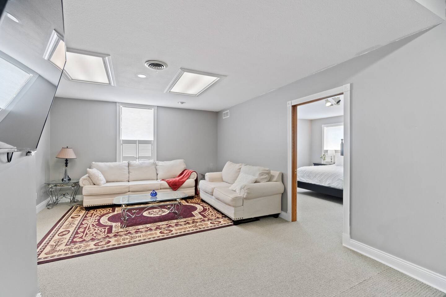 Cozy living area on the second floor with a comfortable couch, large carpet, and a flat-screen TV, perfect for relaxing and unwinding.