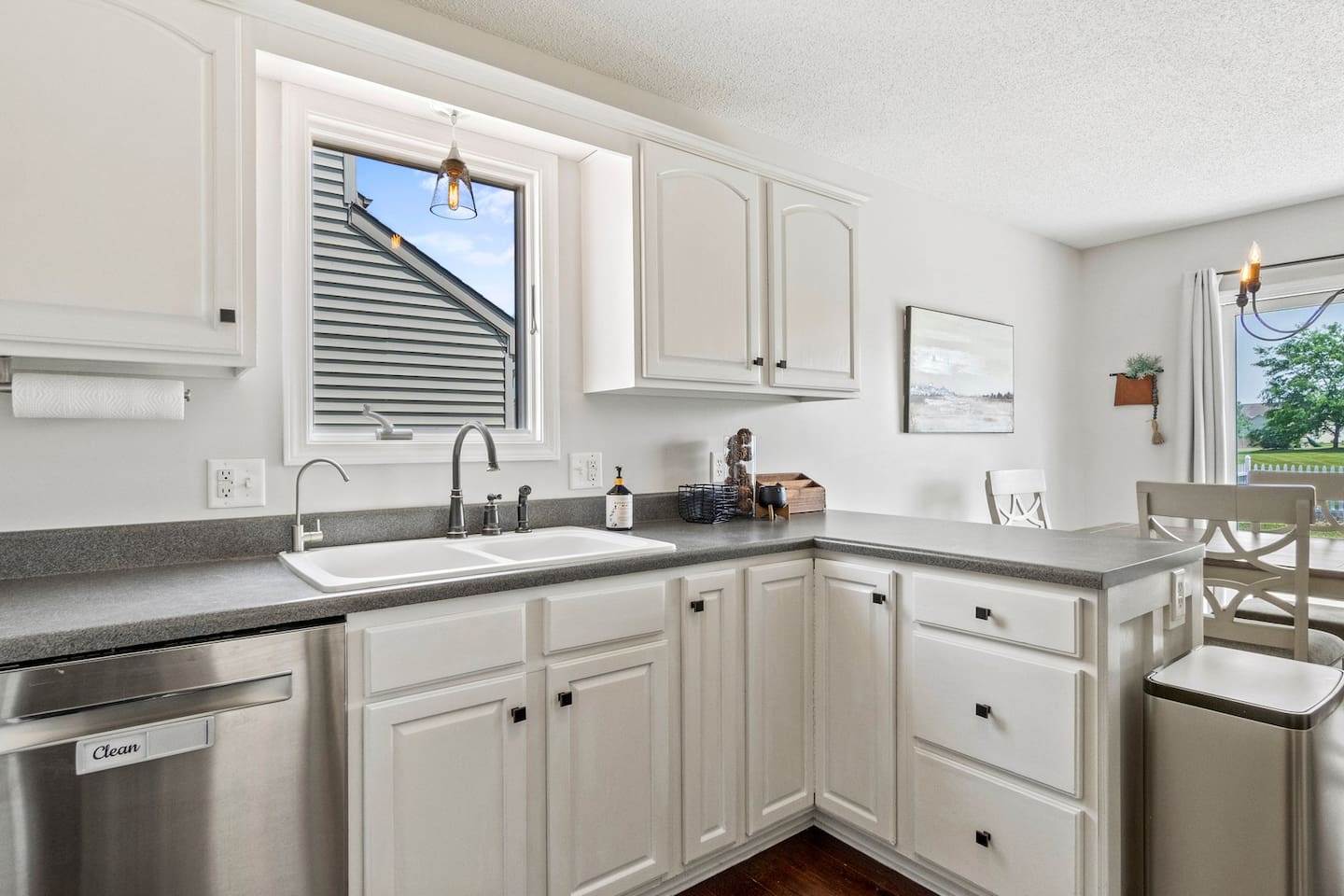 Smooth gray countertops and ample cabinetry provide both prep space and storage, all bathed in sunlight from the window above.

