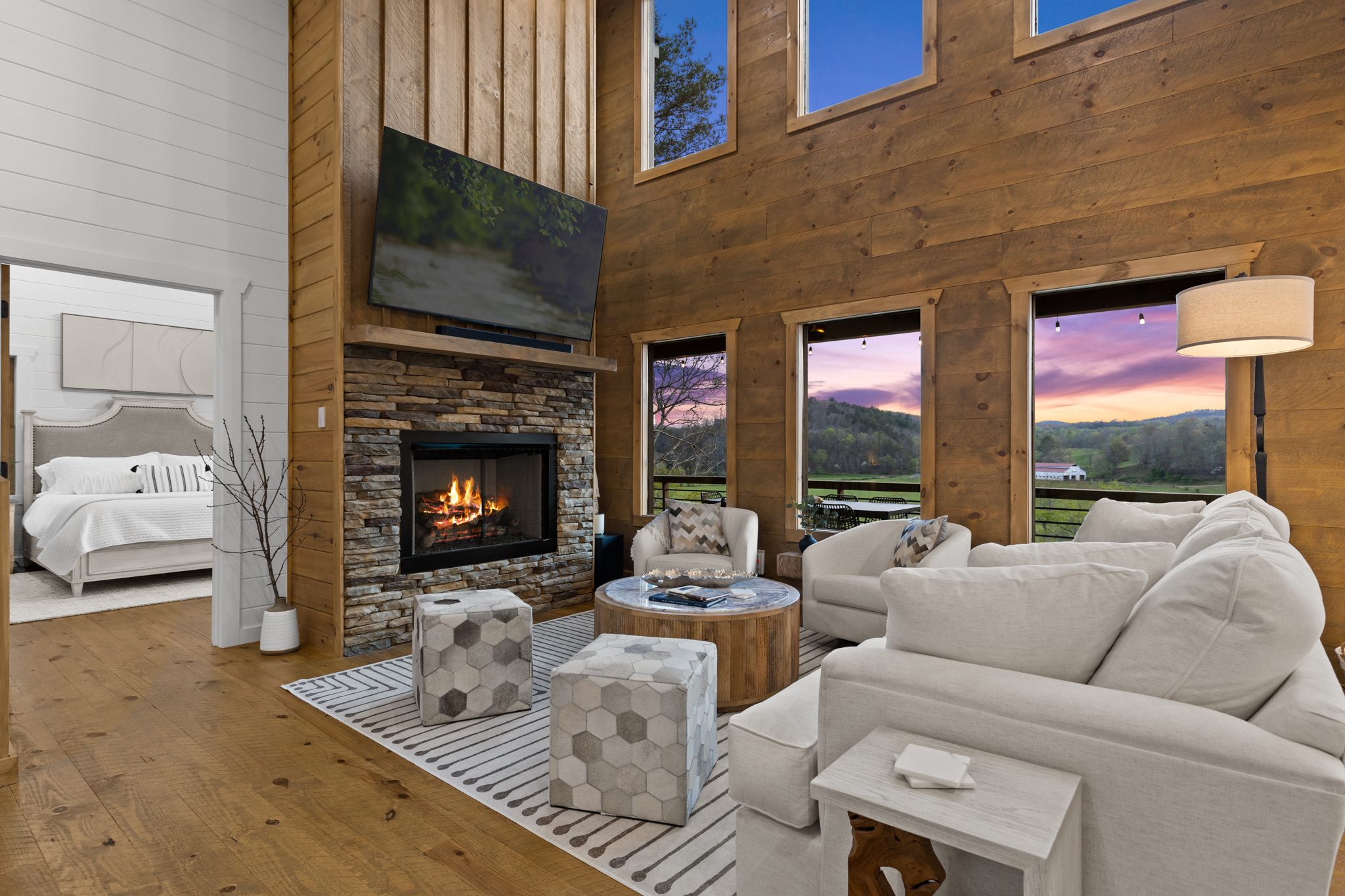 The expansive windows give breathtaking sunset views! Sink into plush white sofas and chairs around the warm fire — the perfect spot for relaxing after a day of adventure.