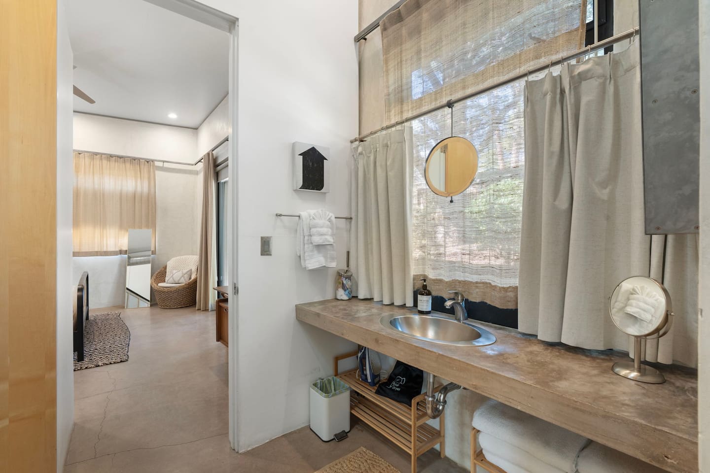 Bright bathroom with a concrete vanity, vessel sink, soft linen curtains, and a clean, modern design.