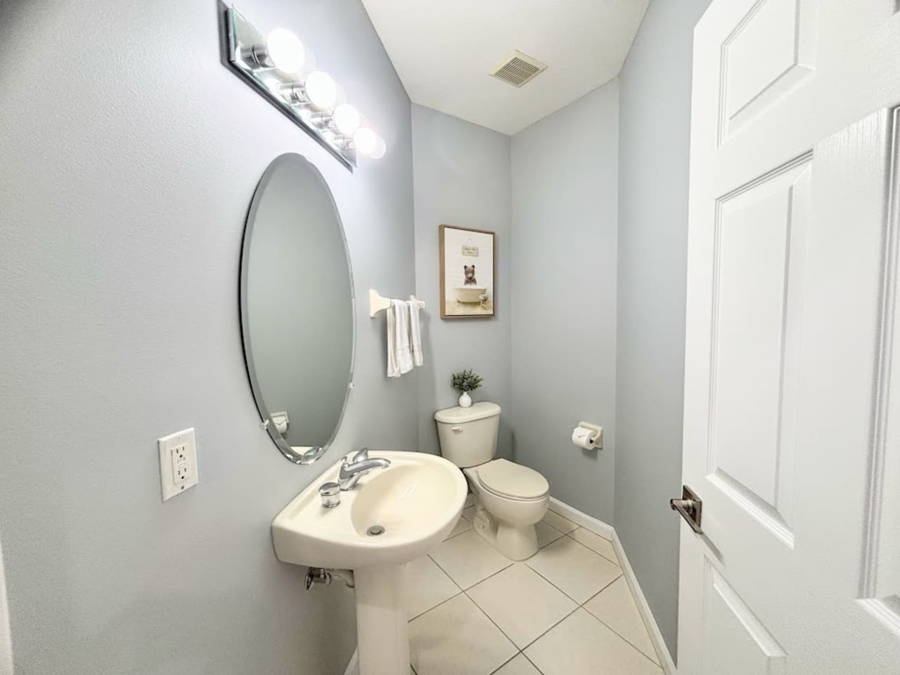 Convenient half bathroom with pedestal sink, tile flooring, and clean modern finishes.