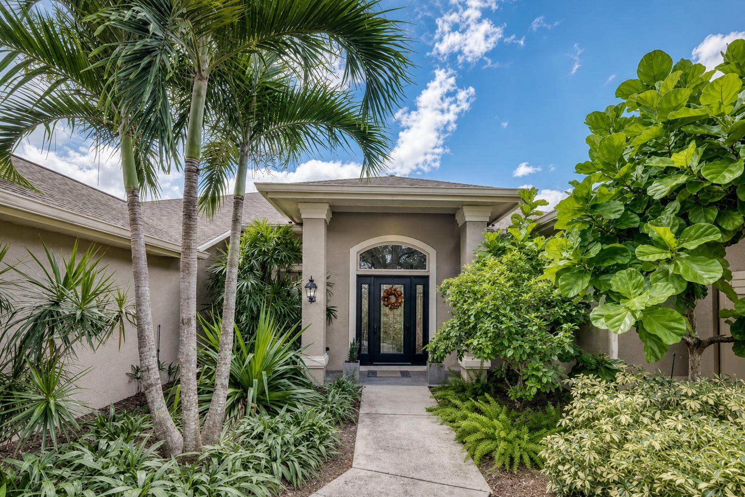 Welcoming front entry framed by lush greenery.