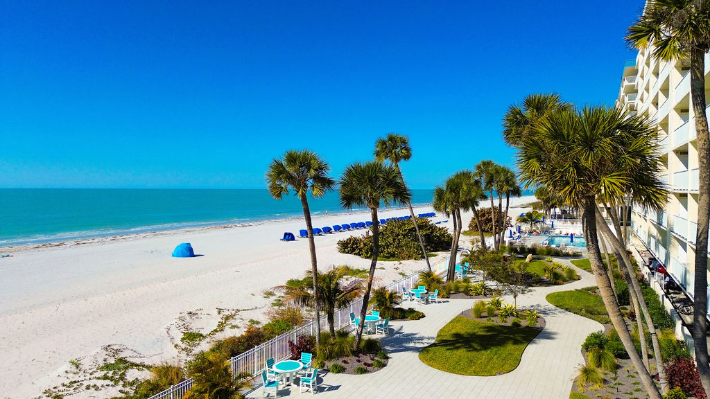 Stunning beachfront resort grounds featuring direct beach access, heated oceanfront pool, tropical landscaping, outdoor seating areas, and breathtaking Gulf Coast views.
