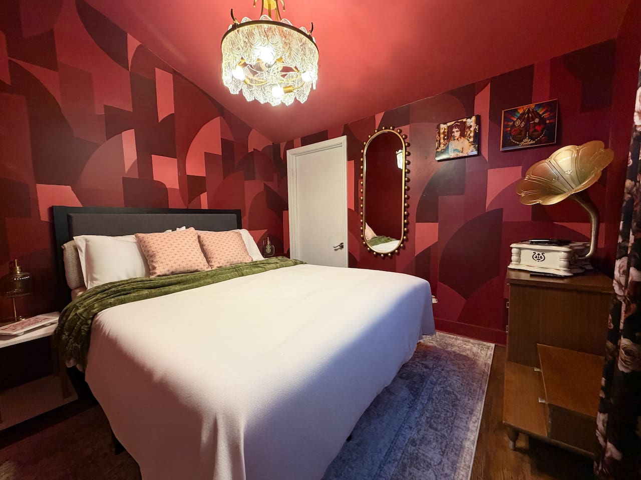 Moody principal bedroom with en suite bathroom, statement art, vintage gramophone décor, and luxurious  bedding. Designed for comfort after long nights exploring New Orleans nightlife and live music. 