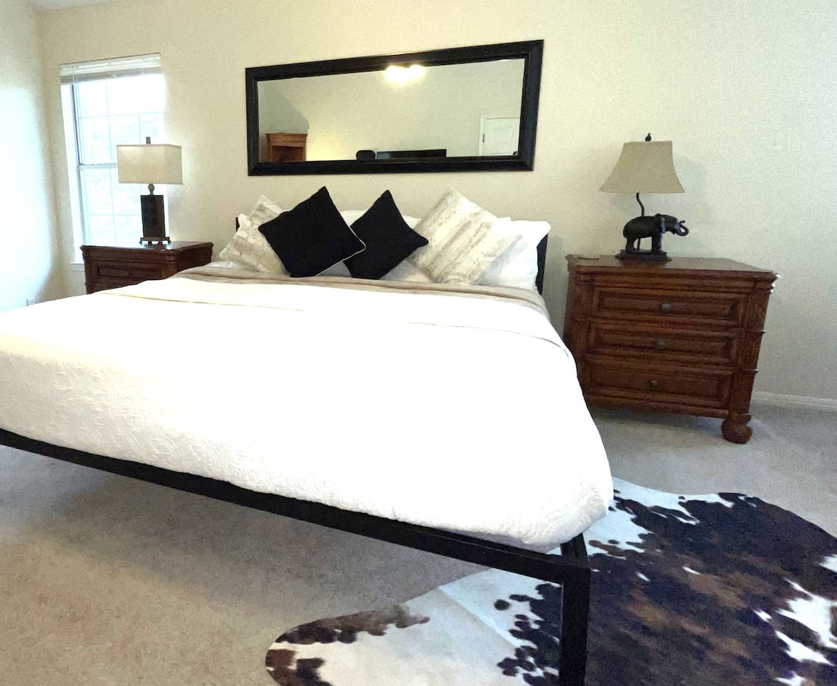 Spacious Master Suite Features King Sleeping, Memory Foam Mattress Topper, Bedside Charging Stations,  40-Inch LED Smart TV, and a Cozy Reading Nook/Office Space.