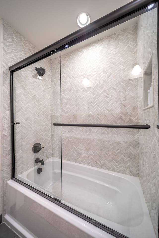 Shared bathroom shower with a tub-shower combo, glass enclosure, and textured tile surround. Designed for comfort and functionality, this space serves Bedroom 3 and common areas with ease.