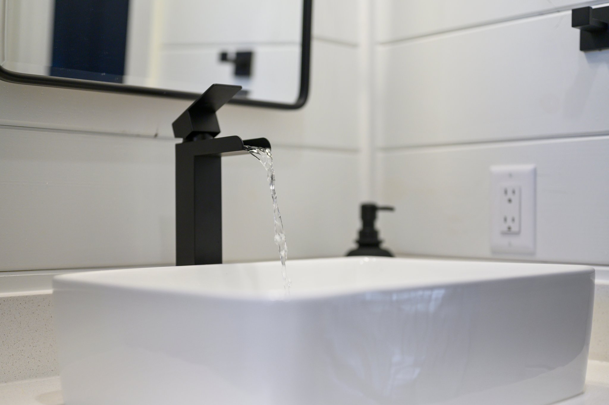 The guest bathroom features sleek black fixtures and crisp white shiplap for a clean, modern look.