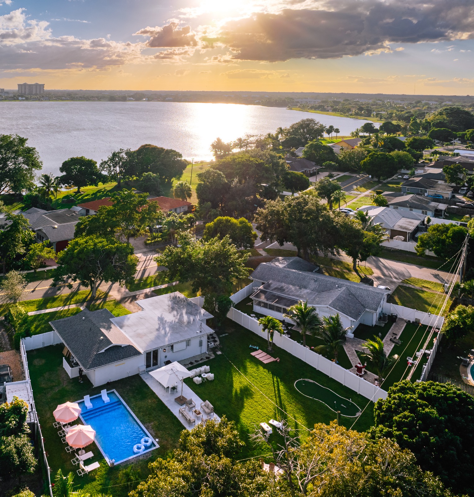 Oversized, fully fenced Palm Beach backyard featuring a heated pool, outdoor dining patio, fire pit lounge, and games.