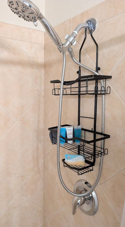 Showers have plenty of storage space, handheld shower heads with multiple spray settings, and basic toiletries including shampoo, conditioner, lotion, and bar soap. 