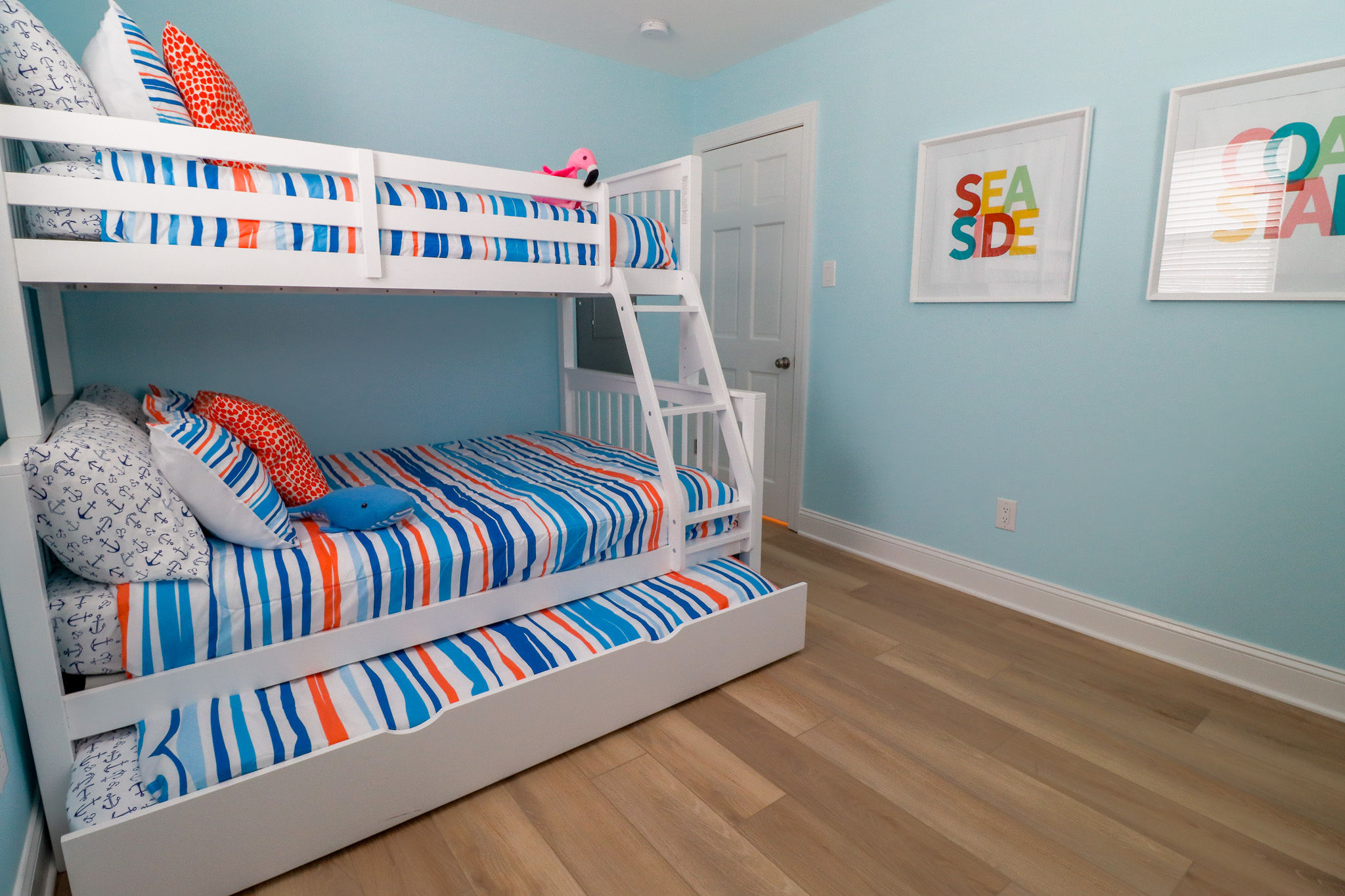 The bunk bedroom features a Twin-Over-Full bunk bed with trundle, a smart tv, a sound machine, a dresser,  and a full length mirror 