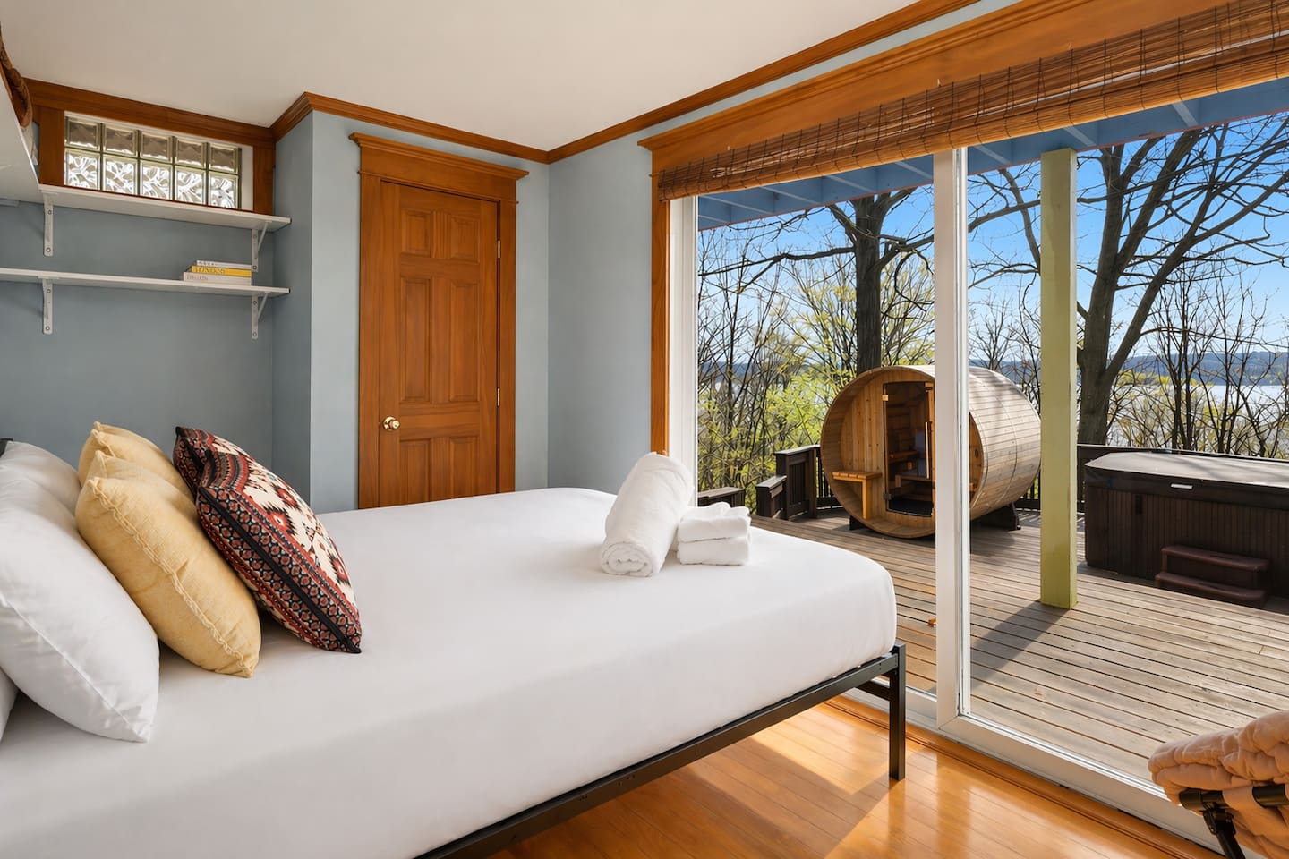 “Enjoy this bright downstairs bedroom featuring a glass door with direct access to the balcony, hot tub, and spa. Relax in comfort with soft bedding and natural light, while vintage suitcase décor adds a charming touch of travel-inspired style.”