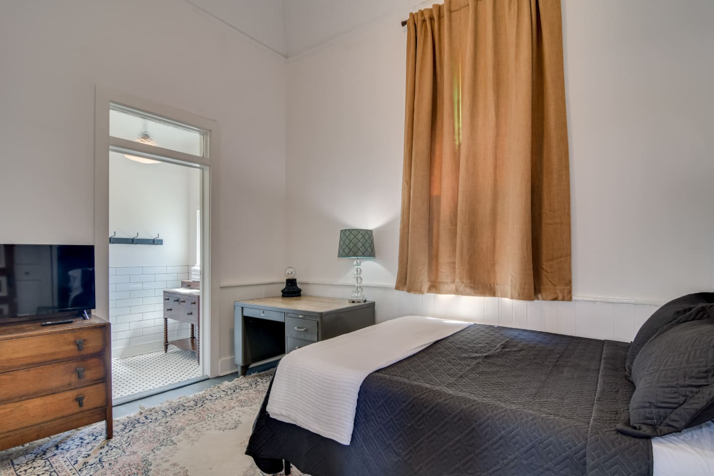 Guest bedroom with cozy queen bed and vintage wood furniture.