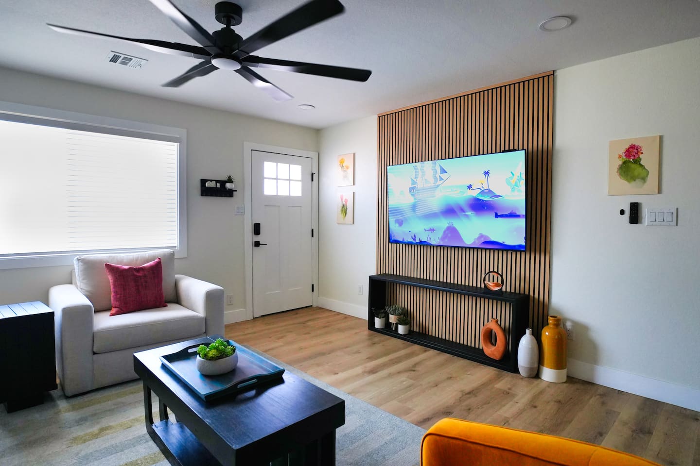 Bright and welcoming living room entrance featuring modern decor, comfortable seating, and a large 65" smart TV. The open layout creates a relaxing space to unwind as soon as you arrive to the Cactus Chill house.