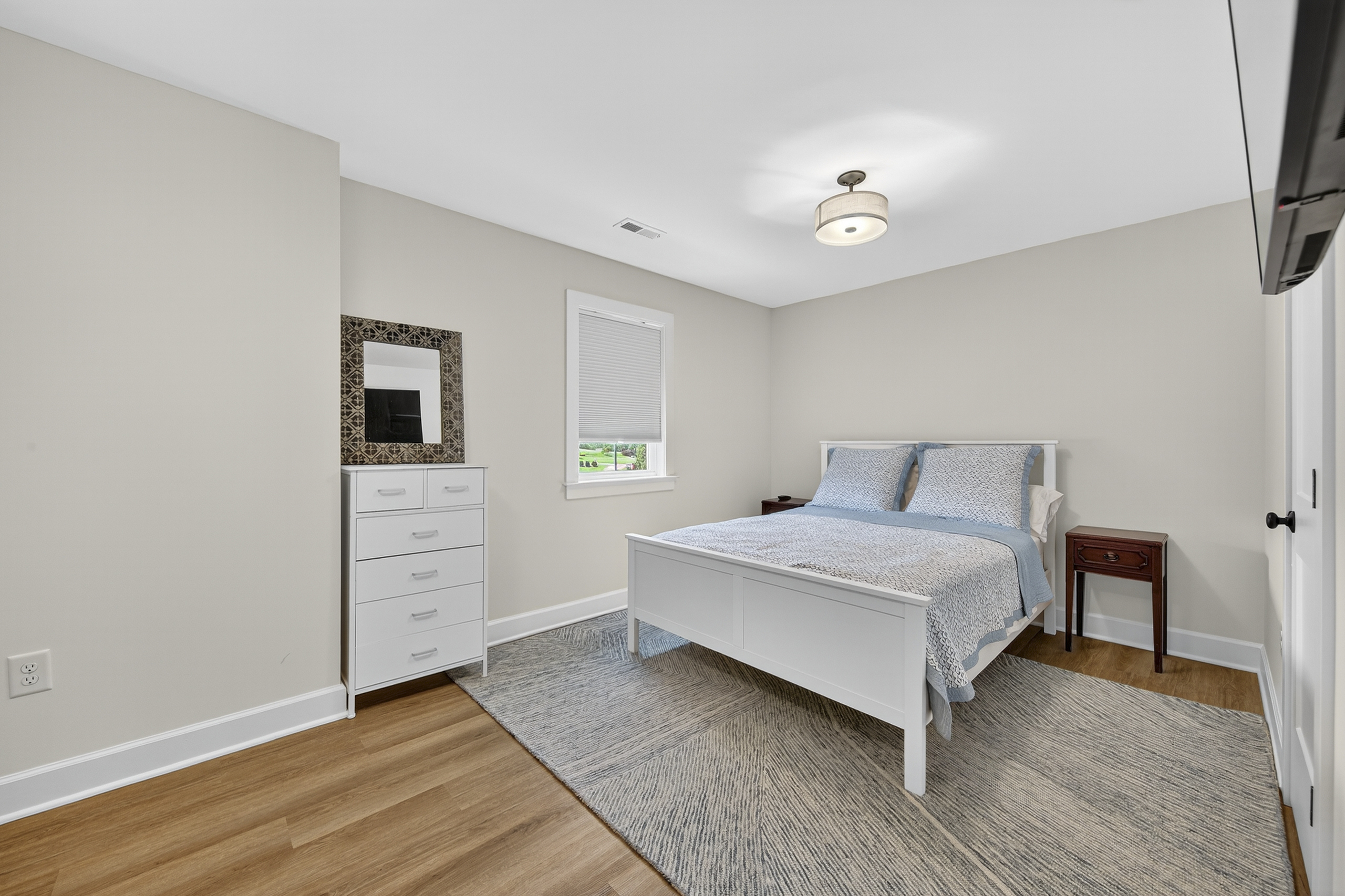Cozy and inviting guest bedroom featuring a fresh white bedframe and calming neutral tones.