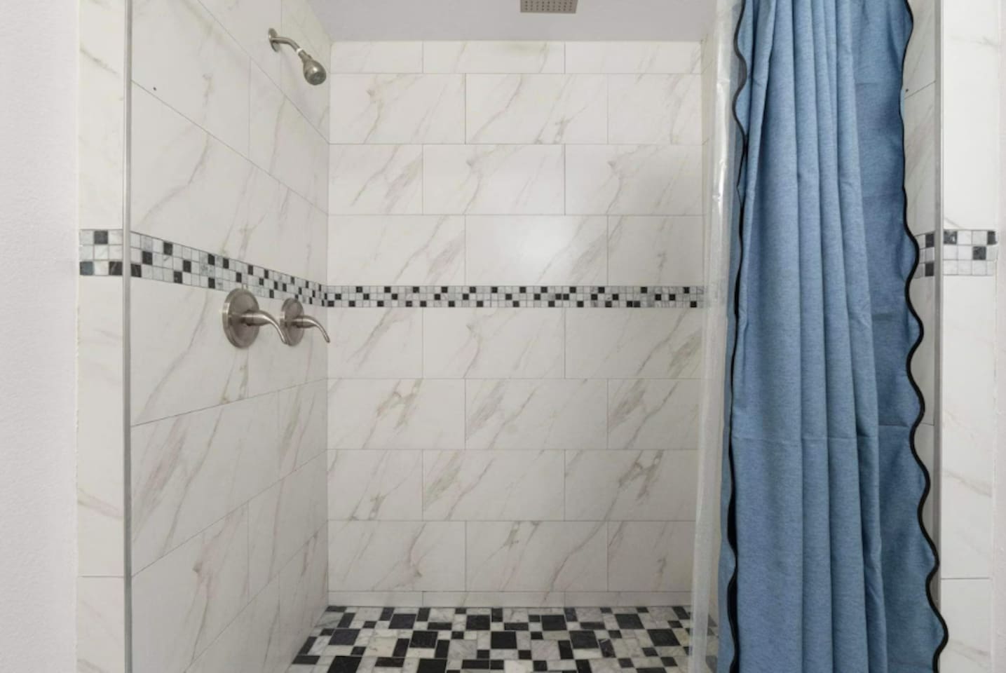 Shower with marble tile and mosaic accents —elegant and spa-inspired for a luxurious experience.