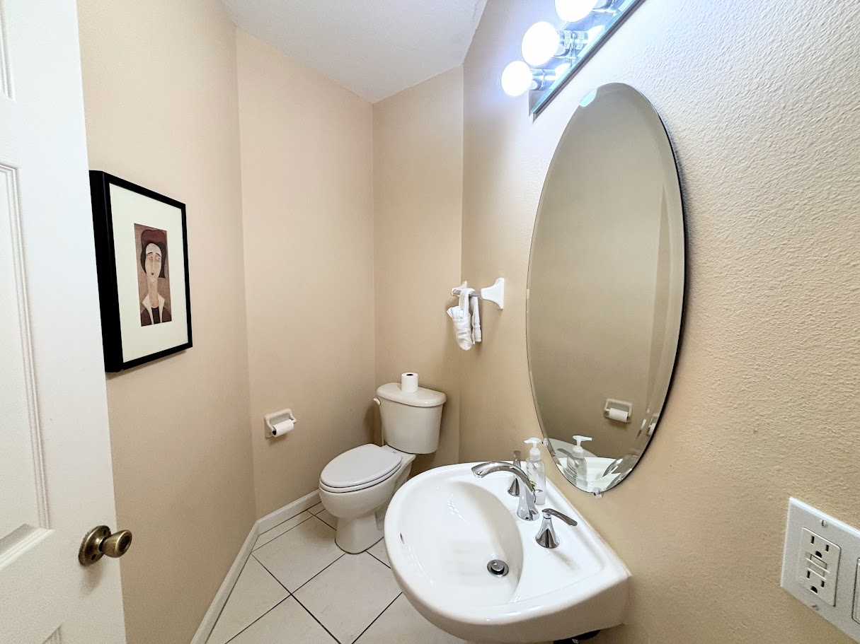 Convenient half bathroom with pedestal sink, tile flooring, and clean, neutral finishes.