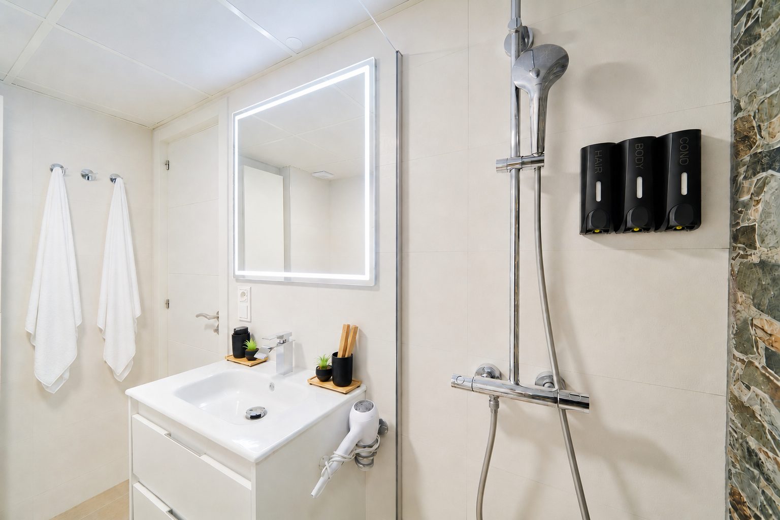 Modern bathroom with walk-in rain shower, stone accent wall, LED mirror, and fresh spa-like touches for your comfort.