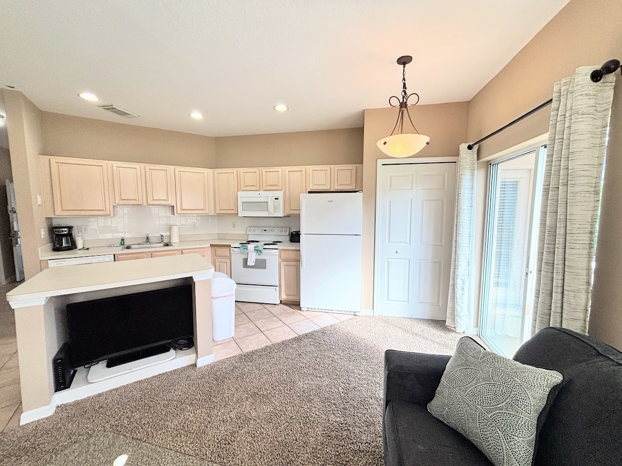 Open kitchen and living space featuring full-size appliances, breakfast bar seating, and easy access to the screened patio.