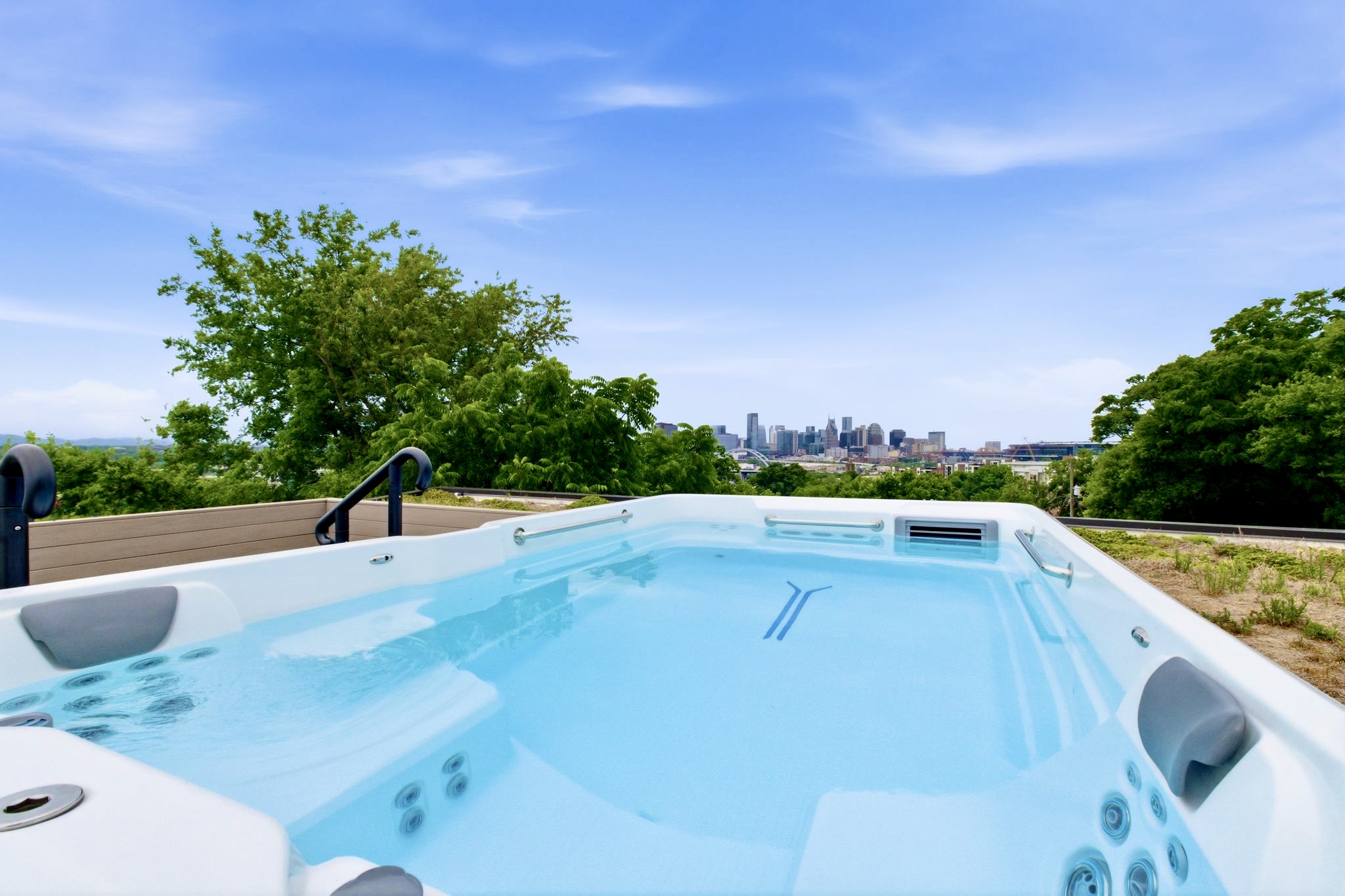Sparkling hot tub surrounded by lush trees & open sky, perfect for a long, restorative soak.
