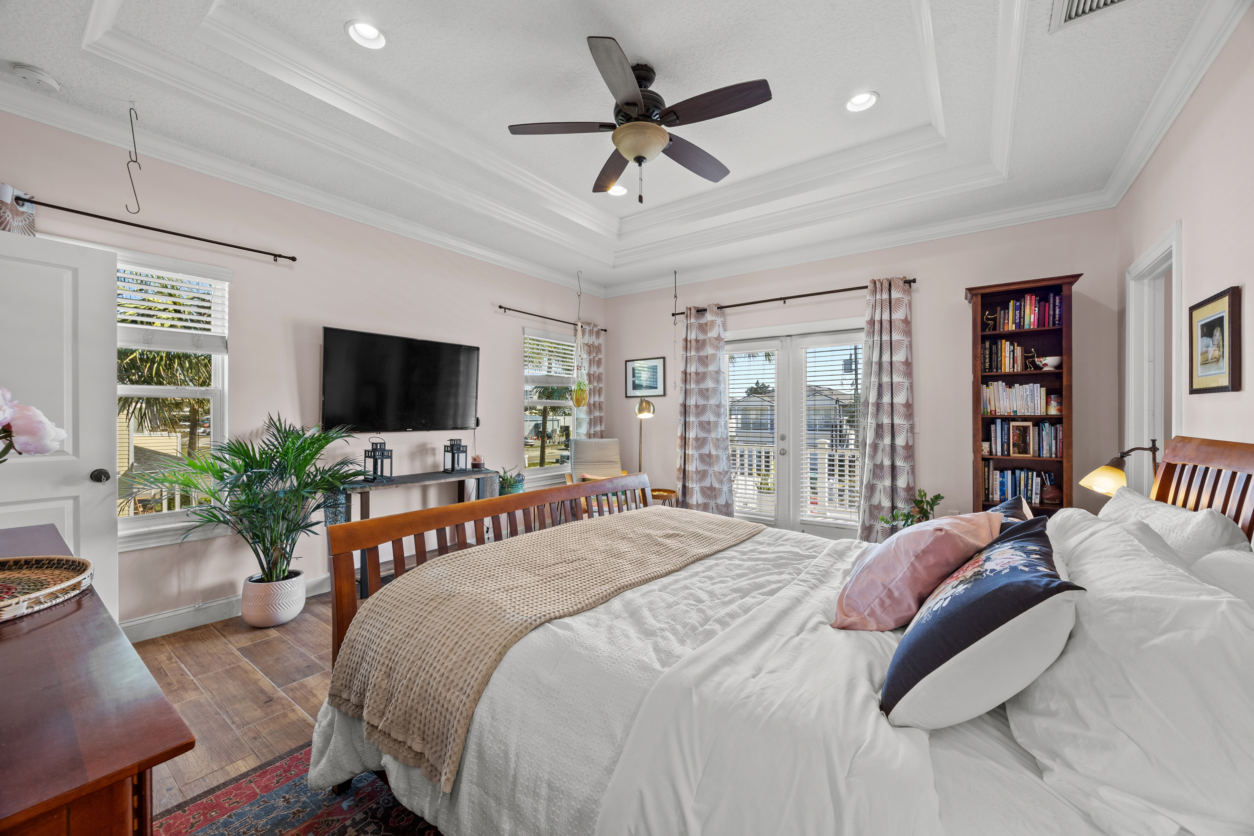 Spacious bedroom with TV, plants, and natural light in Jacksonville Beach family‑friendly rental.