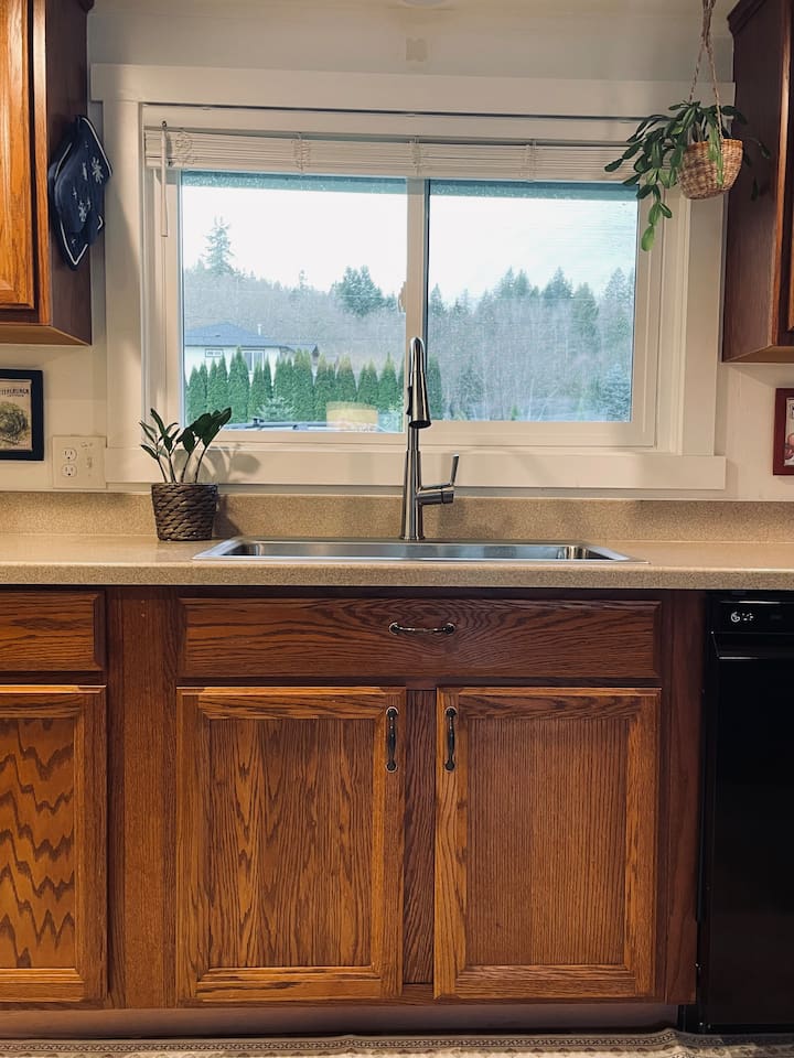 The kitchen sink looks out to bird feeders beyond the window.