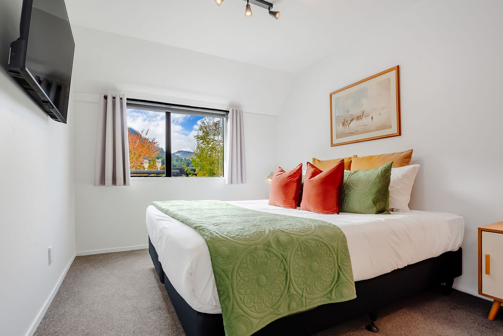 Fernhill Mountain Escape’s downstairs bedroom can be set as a super king or king singles, with a wall-mounted TV and leafy mountain outlook.