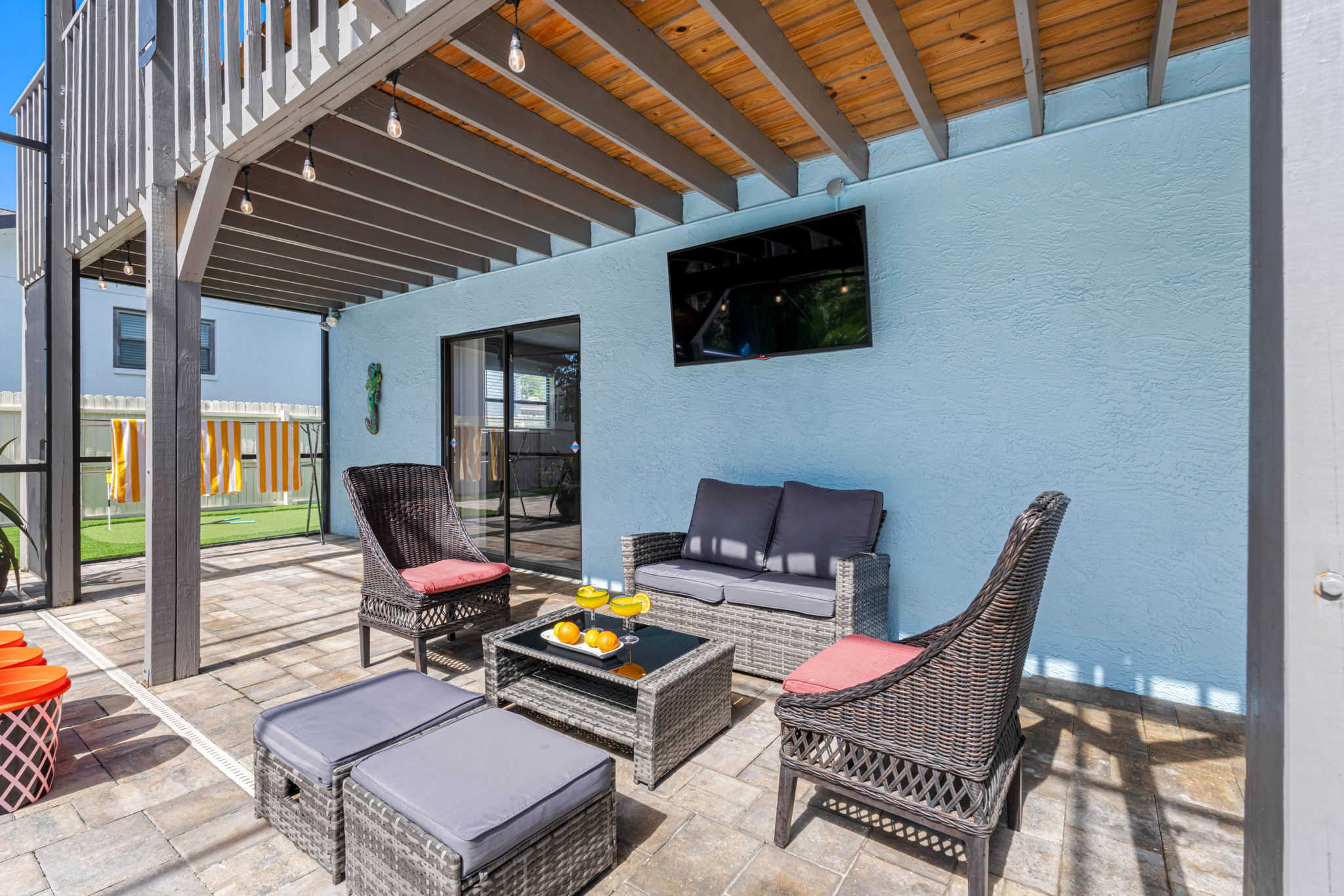Unwind in the shaded sitting area with stylish rattan furniture, vibrant towels, and a view of the pool—perfect for your morning coffee or evening cocktails.