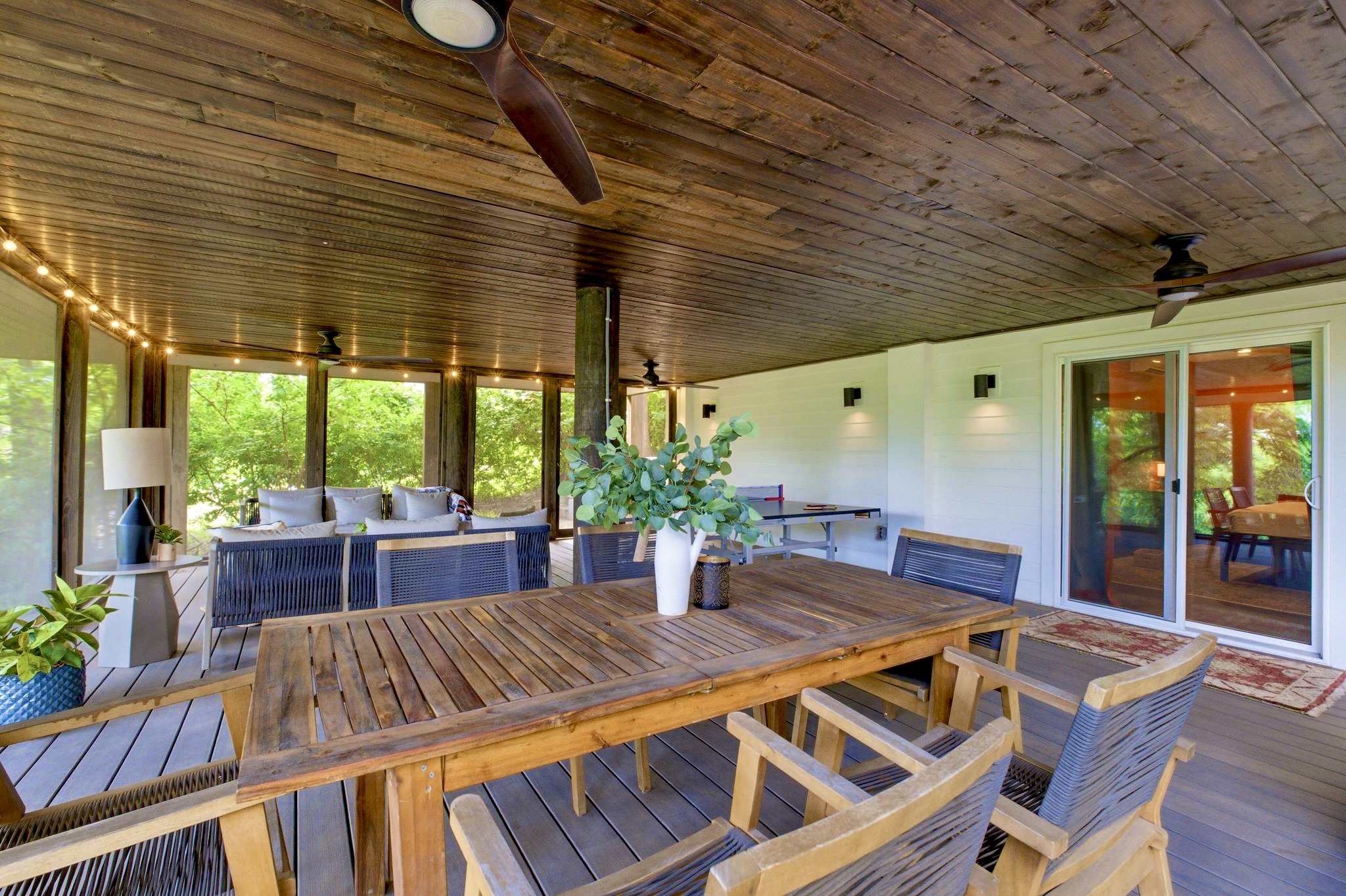 Covered outdoor dining deck w/ a long wood table & ceiling fan — made for long, lazy group meals.
