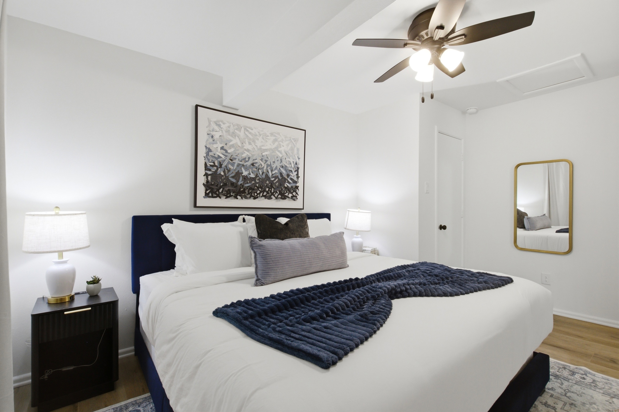 King Bed in Bedroom 1 with bright natural light, Ceiling Fan, and bedside lighting. Restful sleep setup after game day at AT&T Stadium or a day at Six Flags.
