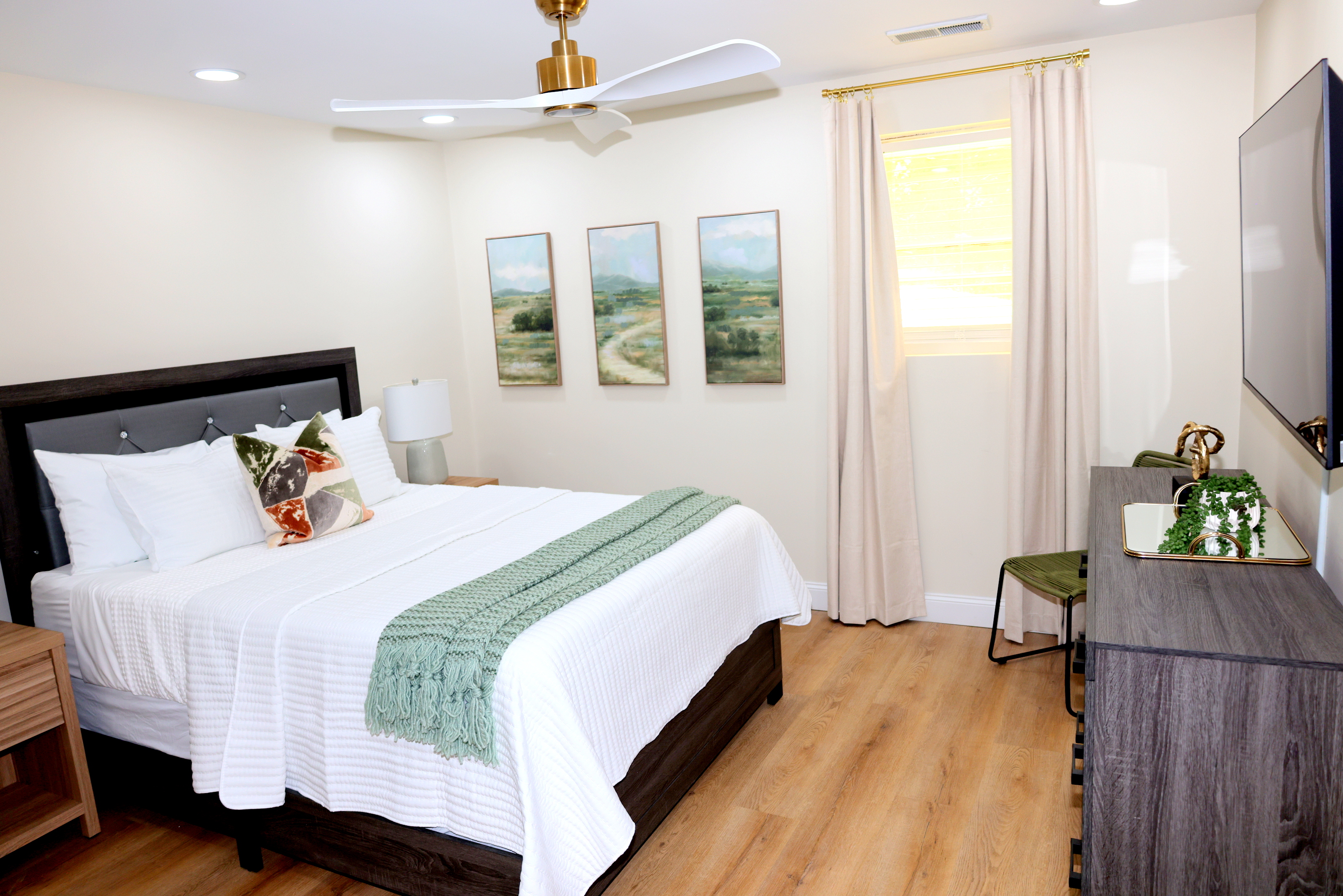 Bright guest bedroom in basement with TV, soft linens, and calming décor