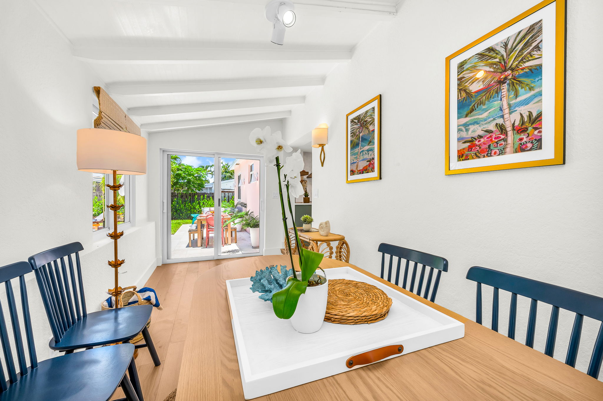 Sun-drenched sophistication—this inviting Florida room features seating for six, a chic bar cart, and panoramic pool views framed by bamboo woven shades. Perfect for intimate meals, morning coffee, or evening cocktails with a tropical backdrop.