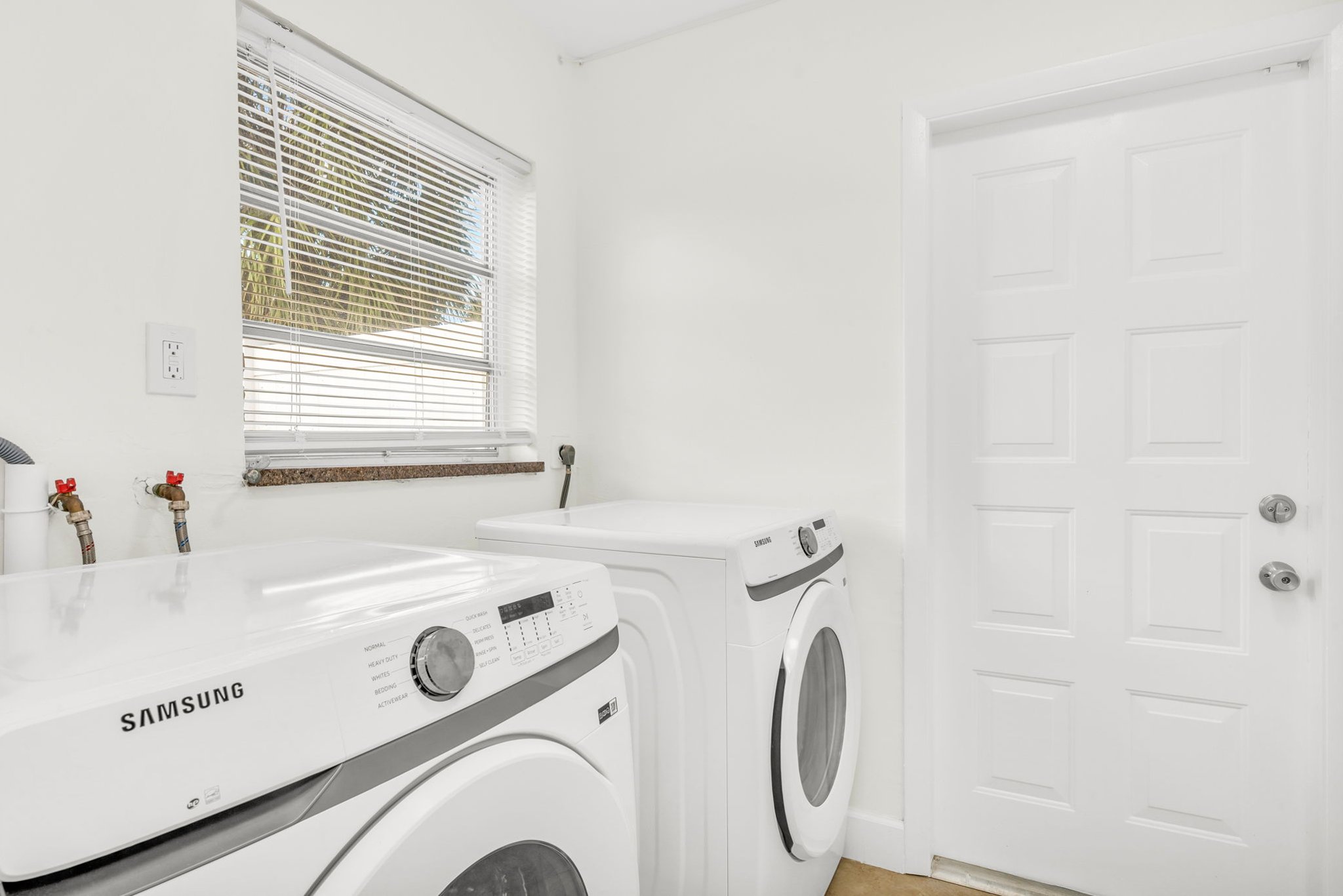 A clean, well-lit laundry room with a full-size Samsung washer and dryer, complete with guest-use detergent for effortless laundering throughout your stay.