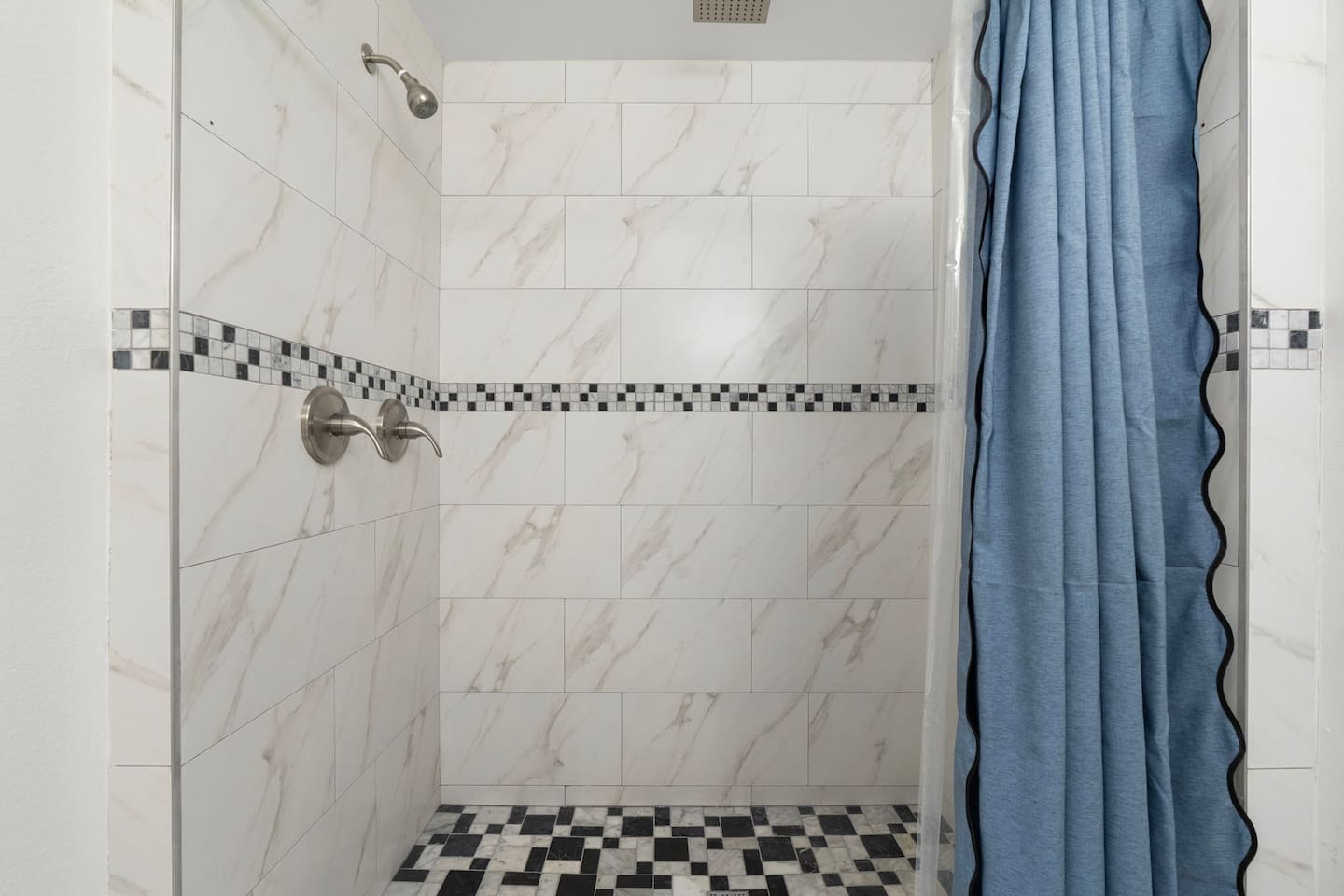 Shower with marble tile and mosaic accents —elegant and spa-inspired for a luxurious experience.