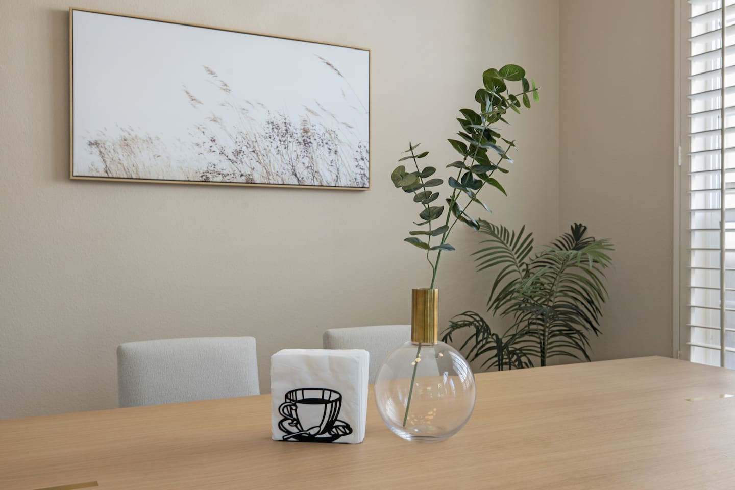 Simple yet elegant table centerpiece with a vase of white flowers and a napkin holder.