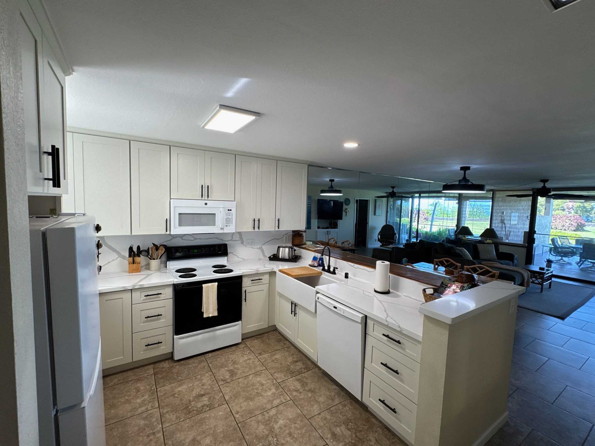 Fully stocked newly remodeled kitchen with farmhouse sink, bright countertops.