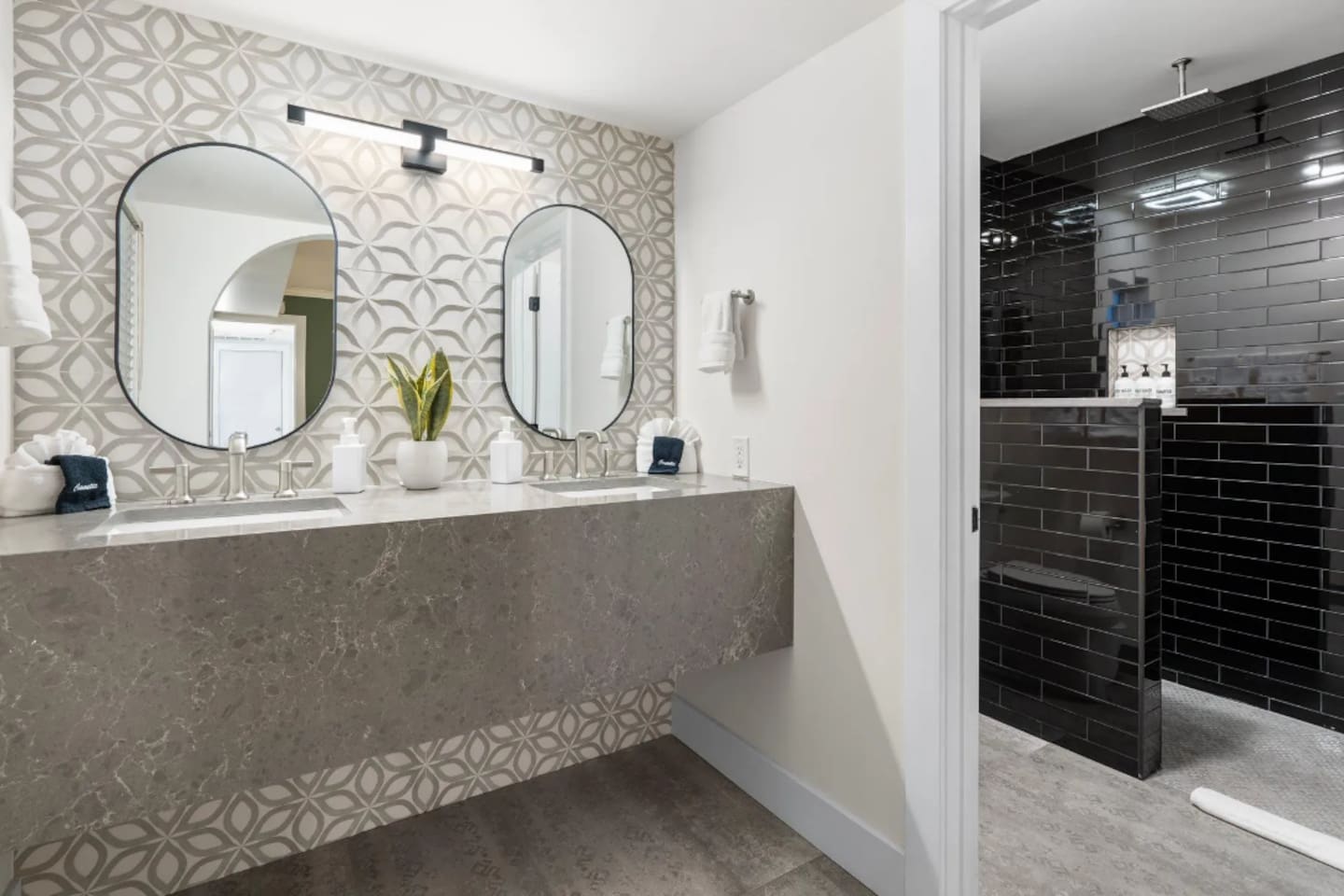 Two oval mirrors and a floating stone vanity make morning routines feel a little more indulgent. Fresh greenery and soft lighting add the finishing touch to this refined space.