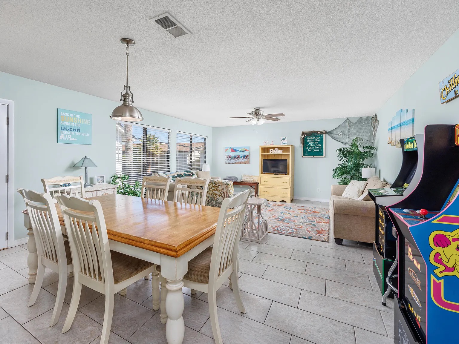 Open-concept living & dining, arcade included. Gather the whole crew around the dining table (seats 6). Natural light pours in through the windows, and yes, those are arcade cabinets in the corner.